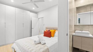Een moderne slaapkamer met een groot bed, een plafondventilator en een inbouwkast.