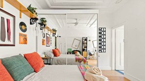 Un dormitorio moderno con una cama grande, almohadas coloridas y una manta de colores del arcoíris.
