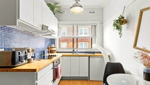 Una cocina compacta con encimera de madera, un lavabo y una ventana con persianas.