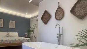 A modern bathroom with a freestanding bathtub, a shower, and decorative wall art. - Apoheo Beach Cabin (El Nido)
