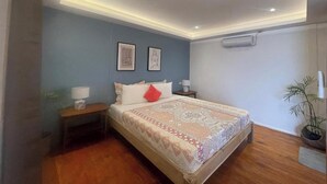 A bedroom with a bed, bedside tables, wall-mounted air conditioning, and framed artwork. - Apoheo Beach Cabin (El Nido)