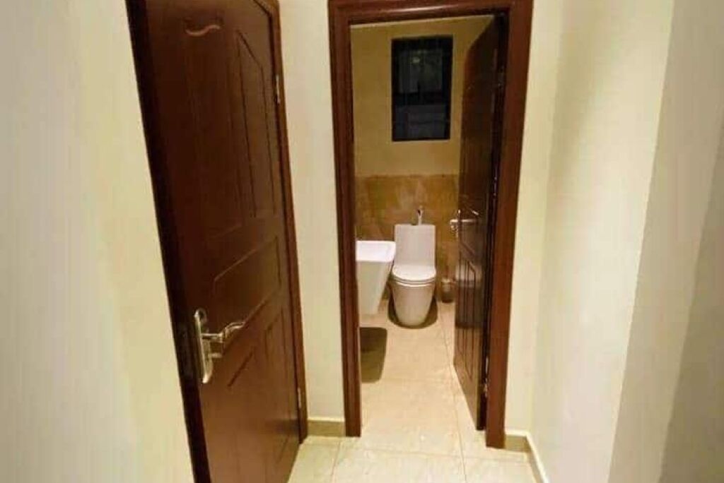 A narrow hallway leading to a bathroom with a toilet and a sink.