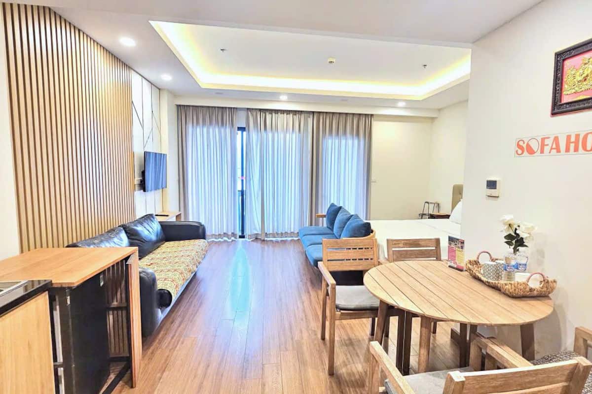 A modern living room with a sofa, a dining table, and a kitchen area.