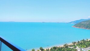 A coastal view with a clear sky, a beach, and a mountainous landscape. - Apartment FLC Quy Nhơn Sea View (Quy Nhon Nam)