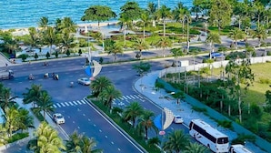 An aerial view of a coastal area with a road, palm trees, and a beach. - Apartment FLC Quy Nhơn Sea View (Quy Nhon Nam)