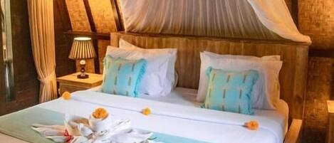 A bed with a canopy, pillows, and a flower arrangement.