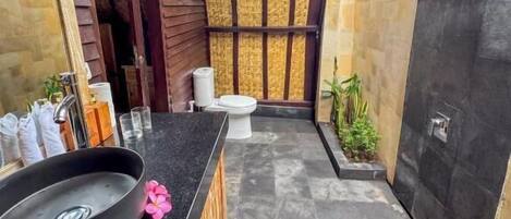 Un baño moderno con un lavamanos negro, detalles de madera y piso de baldosas.