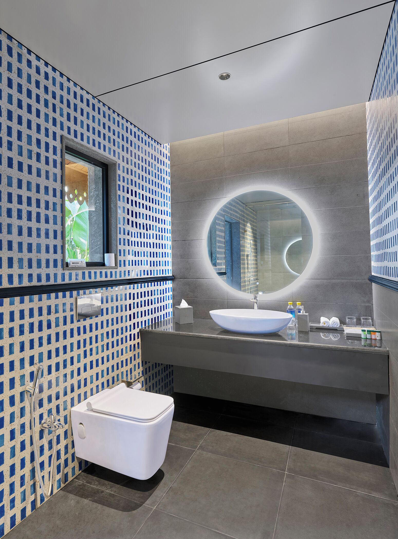 A modern bathroom with a large sink, a mirror, and a toilet.