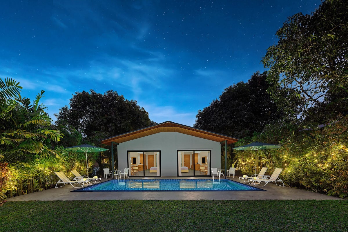 Une maison moderne avec une piscine, deux portes et deux parasols.