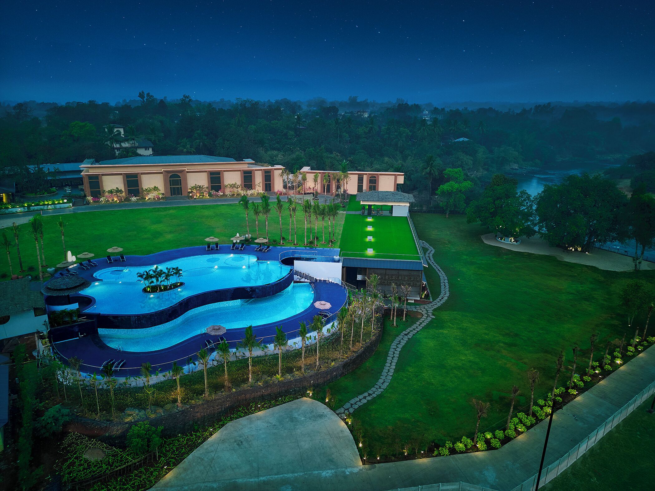Un resort con una gran piscina, un césped bien cuidado y un edificio de techo plano.