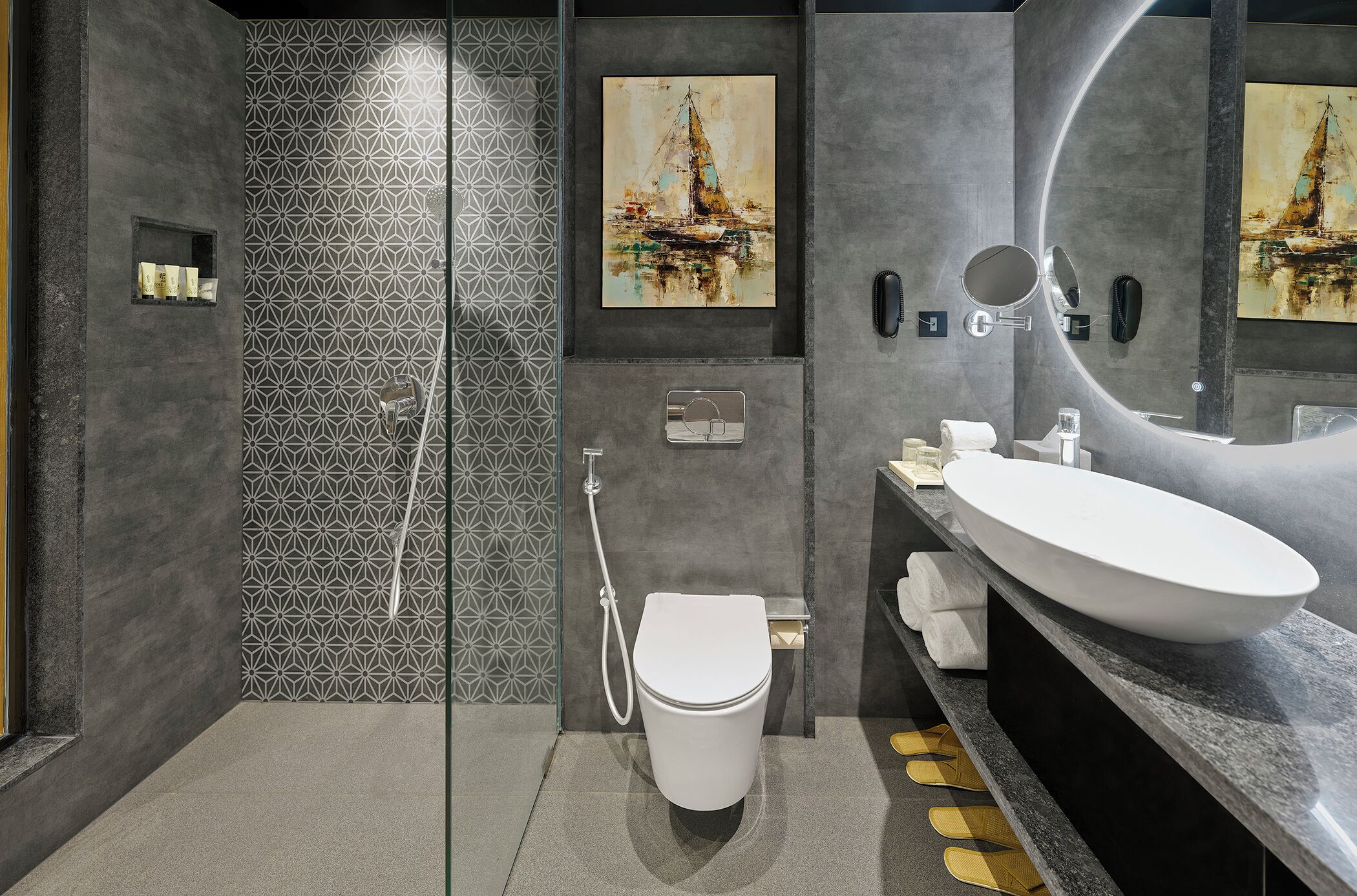 A modern bathroom with a large mirror, a white sink, and a glass-enclosed shower.