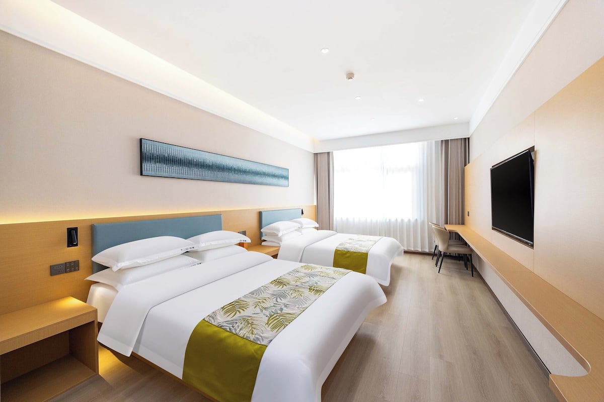 Une chambre d’hôtel avec deux lits, un téléviseur à écran plat, un bureau et une grande fenêtre.