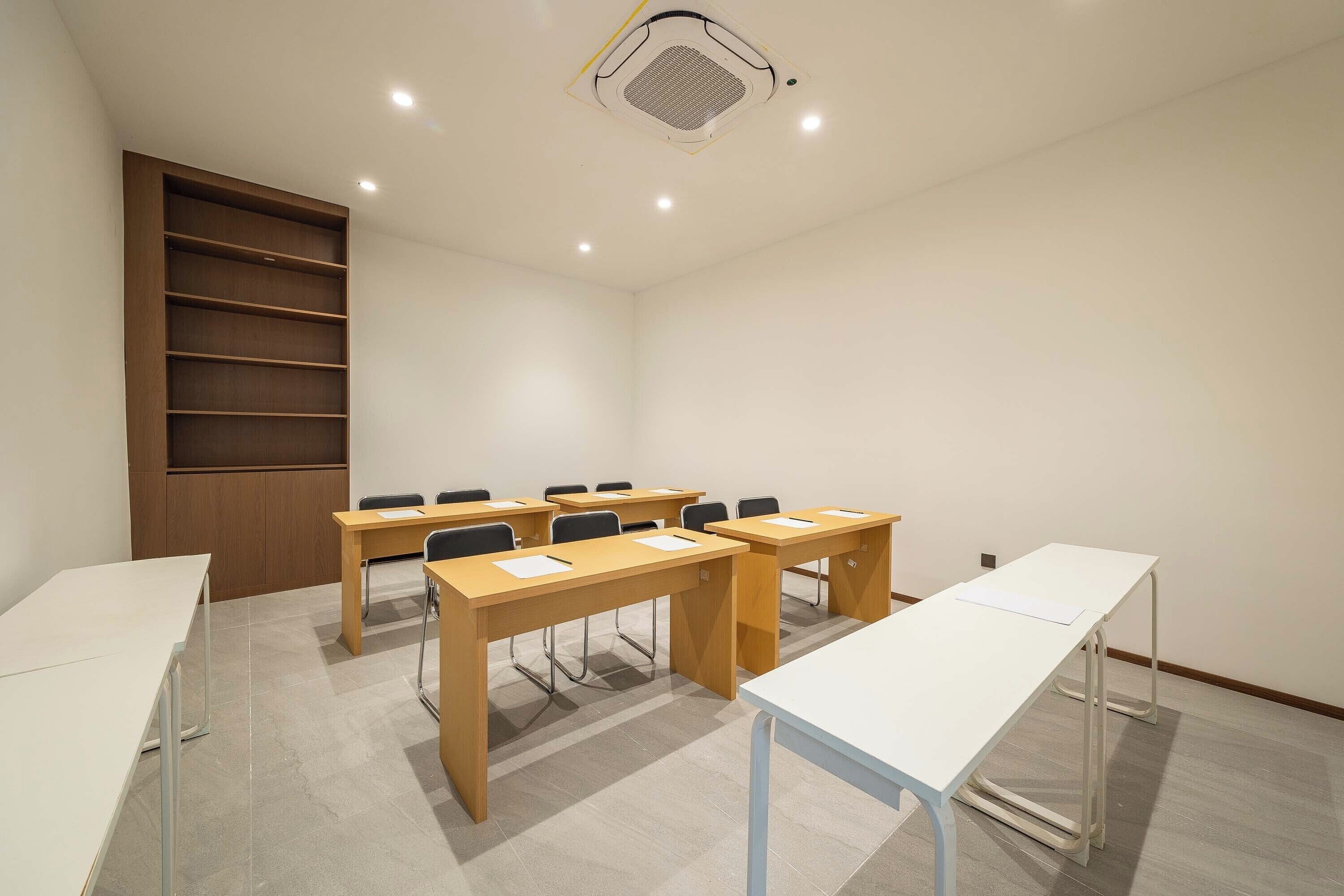 A conference room with a long table, chairs, and a wooden shelving unit.