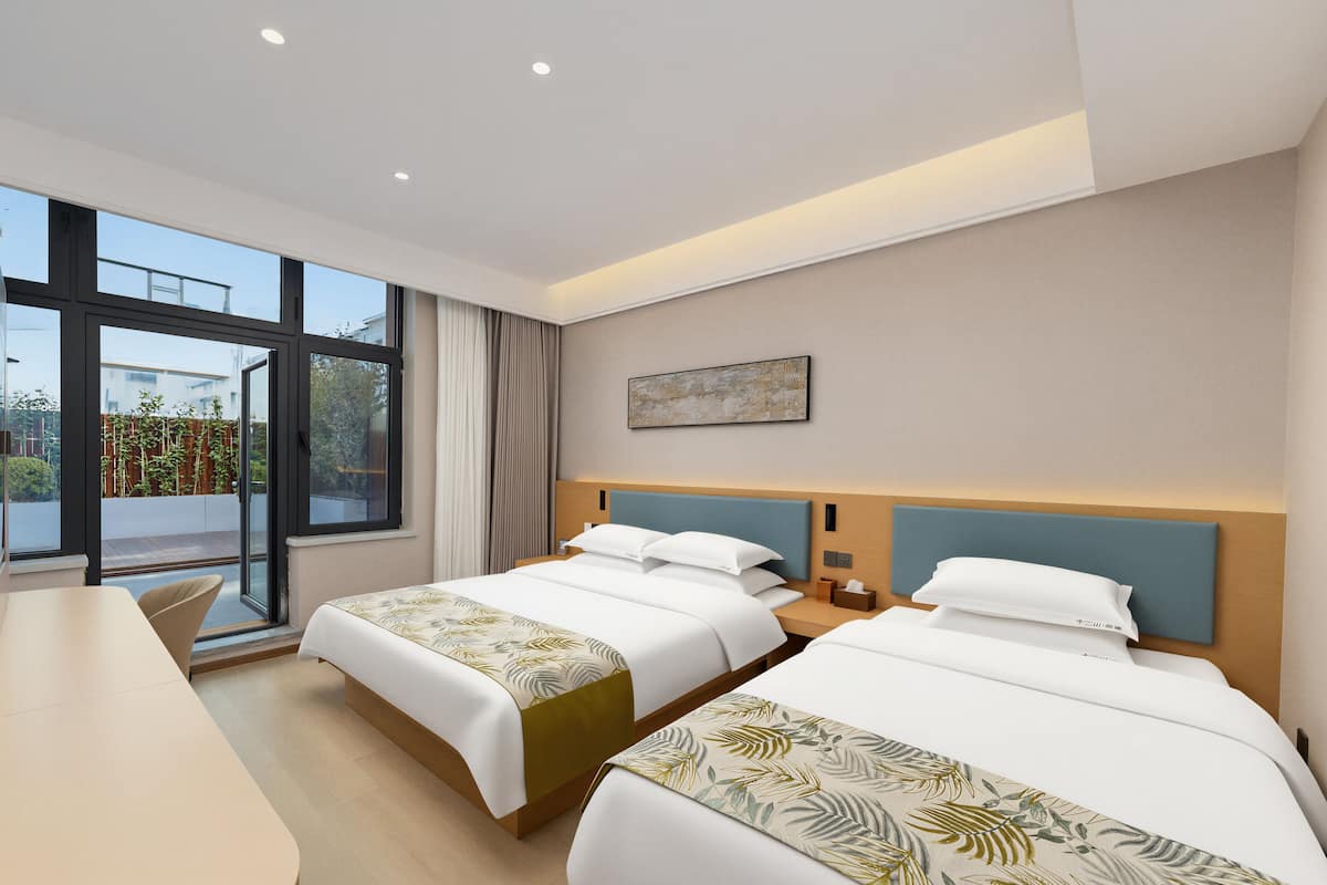 Une chambre d’hôtel moderne avec deux lits, un bureau et de grandes fenêtres.