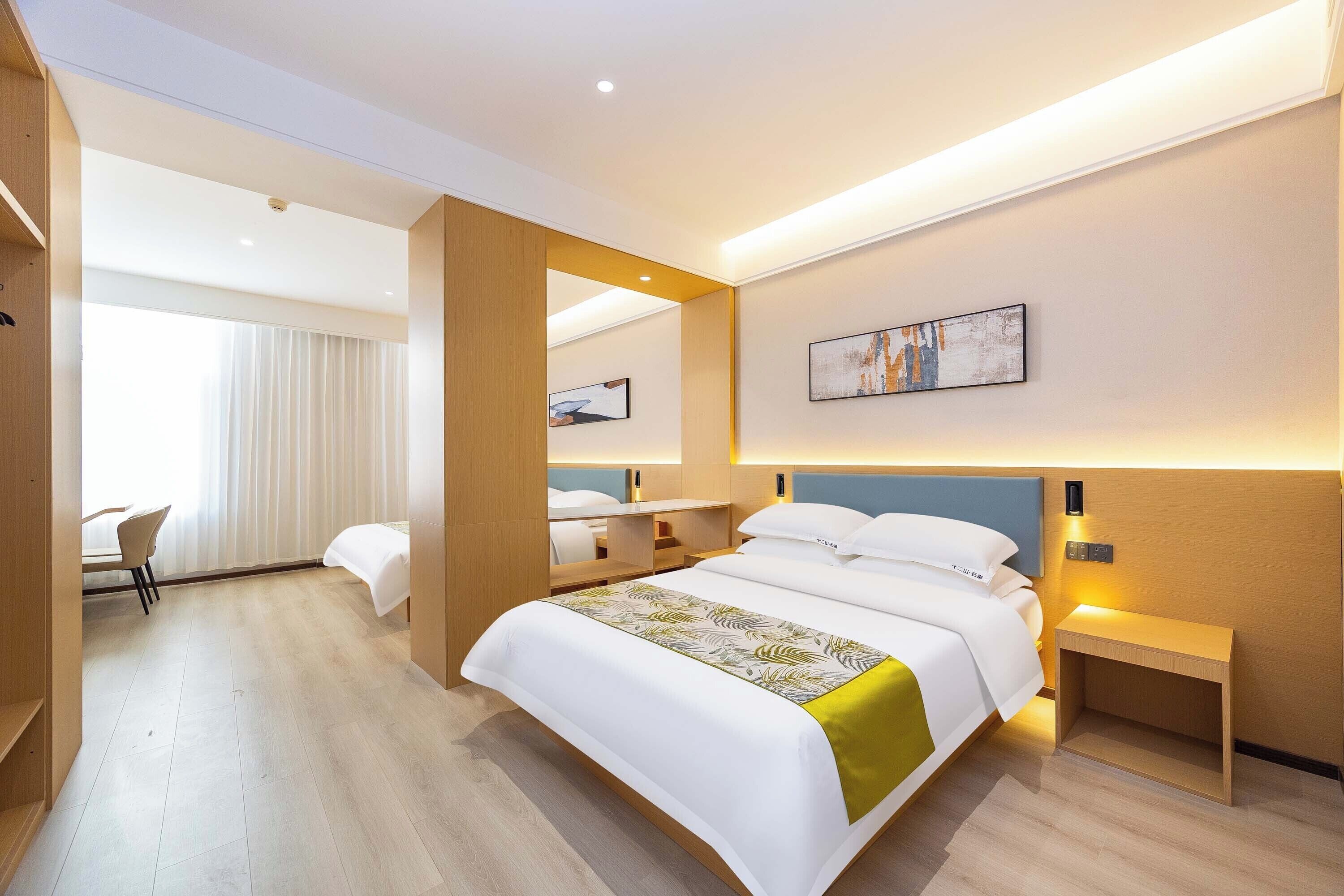 Een moderne hotelkamer met een groot bed, nachtkastjes, een bureau en een stoel.