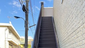 Una escalera metálica con superficie texturizada que conduce a un edificio de fachada blanca.