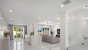 A modern interior with a marble floor, a reception area, a seating area with a sofa, and a television displaying the word "NET". - LUX The Serene Springs Villa 2 (Dubai)