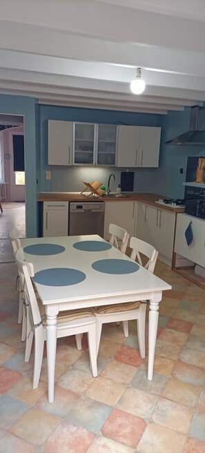 Une cuisine avec une table blanche, des centres de table bleus de forme circulaire et des armoires blanches.