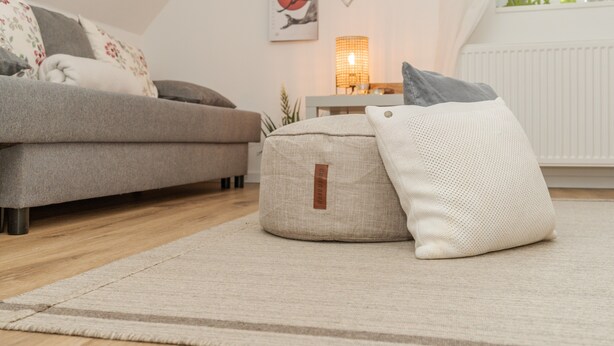 A cozy living room with a sofa, a round ottoman, and a lamp. - Black Forest Apartment "Onkel Franz" for 4 Guests & Baby, Pets Welcome, Near Europa Park (Ohlsbach)