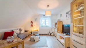 A cozy living room with a sofa, coffee table, and TV stand. - Black Forest Apartment "Onkel Franz" for 4 Guests & Baby, Pets Welcome, Near Europa Park (Ohlsbach)