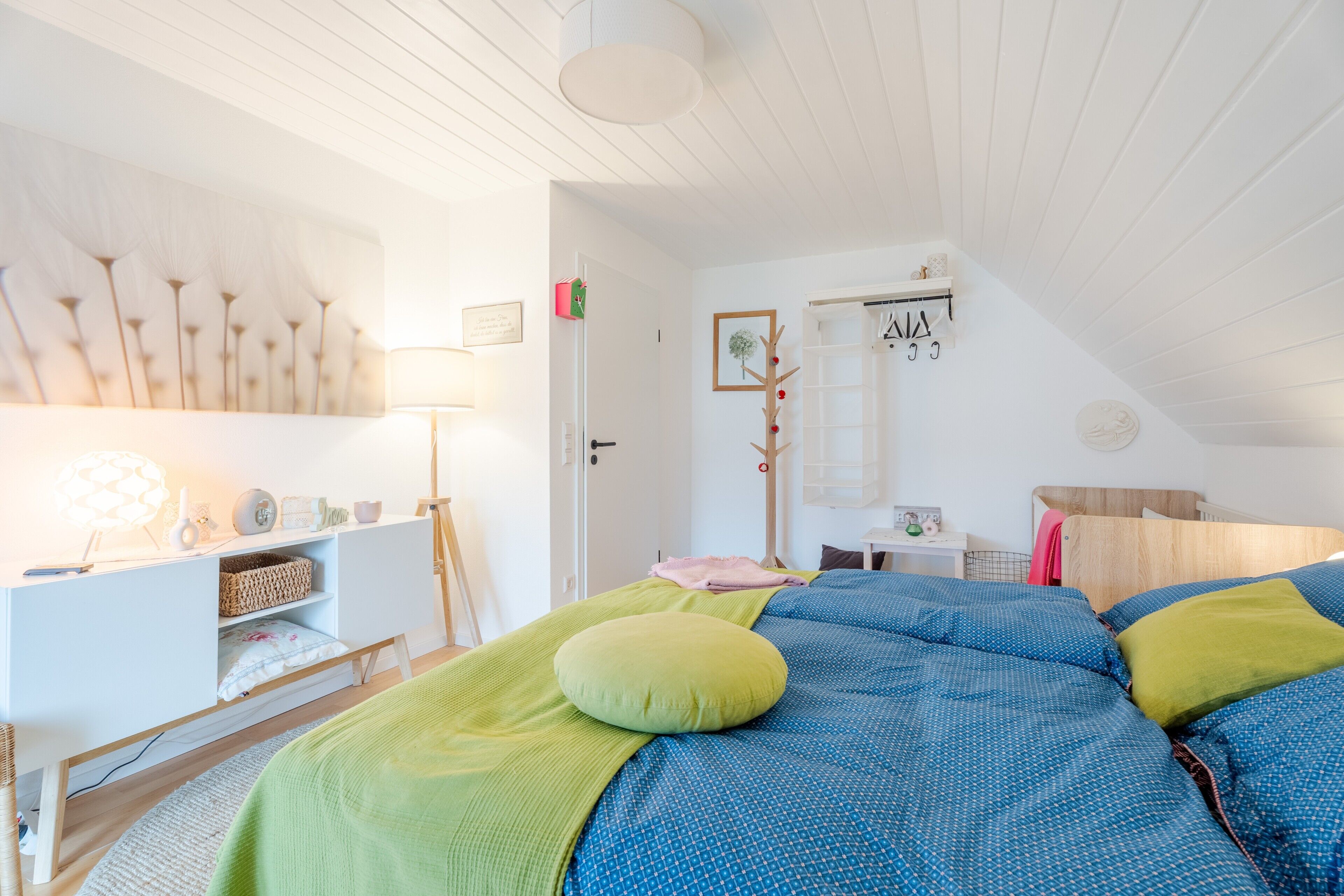 Un dormitorio con cama, mesita de noche, lámpara y estante en la pared.