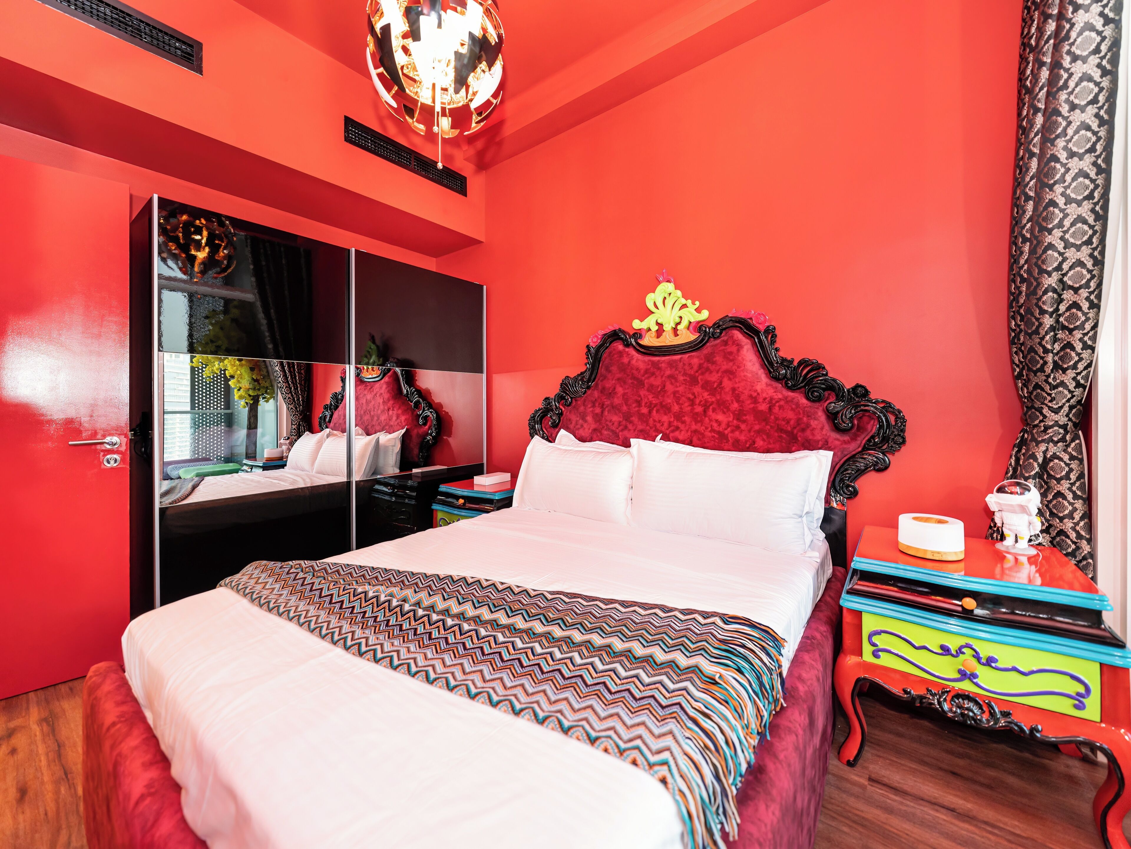 Ein Zimmer mit einem großen Bett, einem Spiegel und einer roten Wand.
