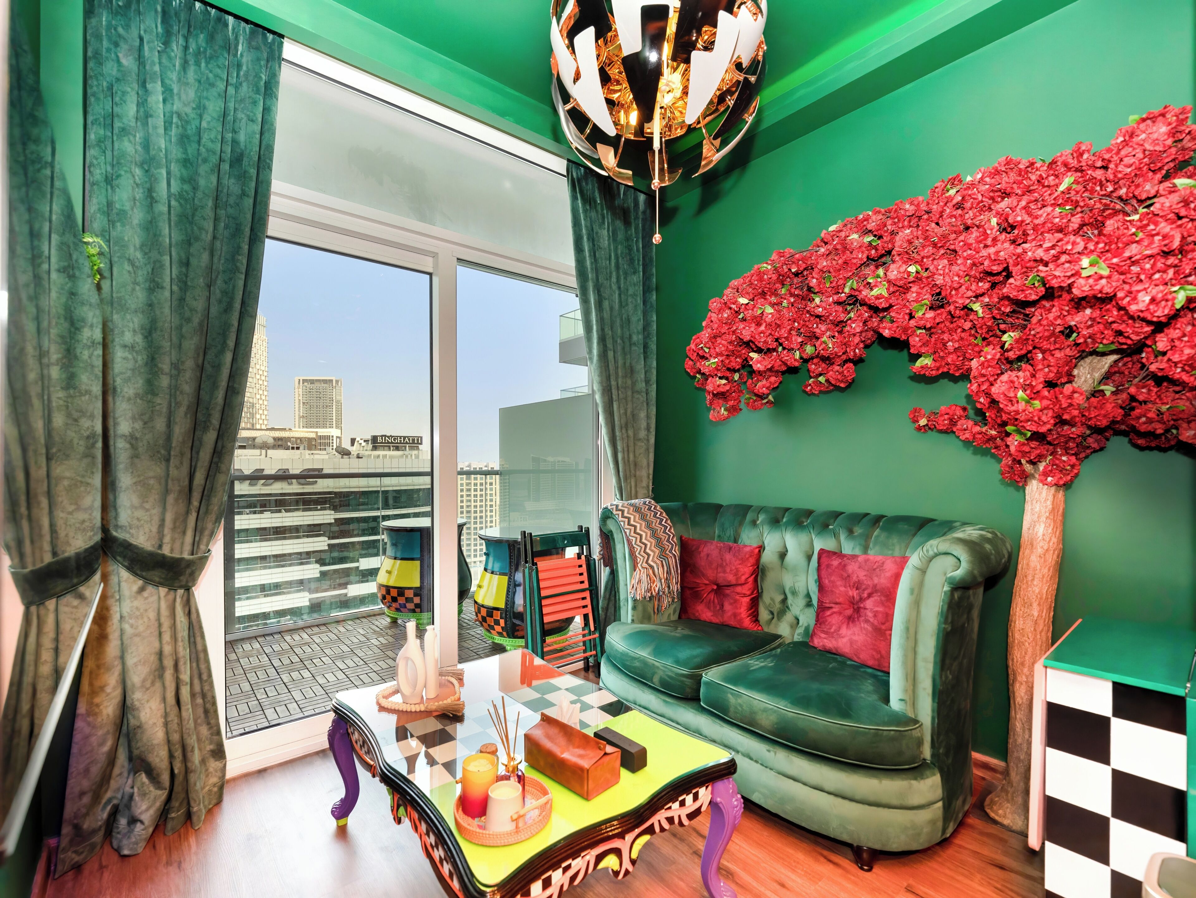 A modern living room with a green sofa, a checkered coffee table, and a decorative tree.