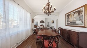 A dining room with a large wooden table, red upholstered chairs, a chandelier, and a painting on the wall. - Historic & Lovely - Huge Backyard, Mother-In-Law Apt out back! (Sarasota)