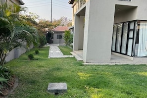 A modern building with a paved pathway leading to a gated entrance.