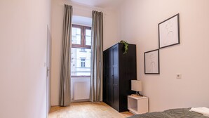 A bedroom with a bed, a wardrobe, a bedside table with a lamp, and a window with curtains. - Charming 2BR Apt Vienna Long Stay (Vienna)