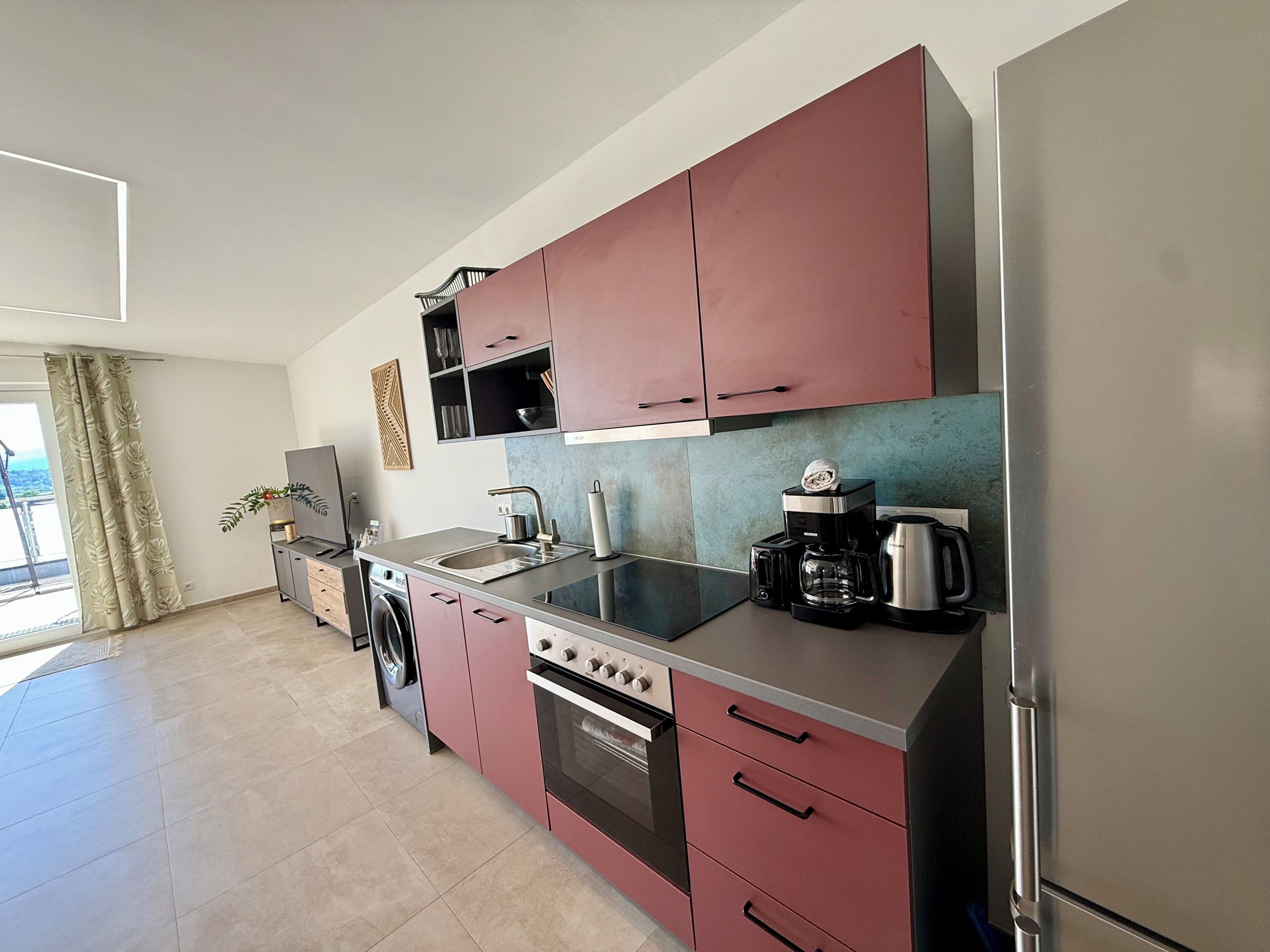 A modern kitchen with a built-in oven, a coffee maker, and a refrigerator.