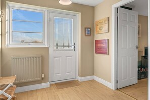 A hallway with a white door, a radiator, a window with a view, and a framed sign on the wall.