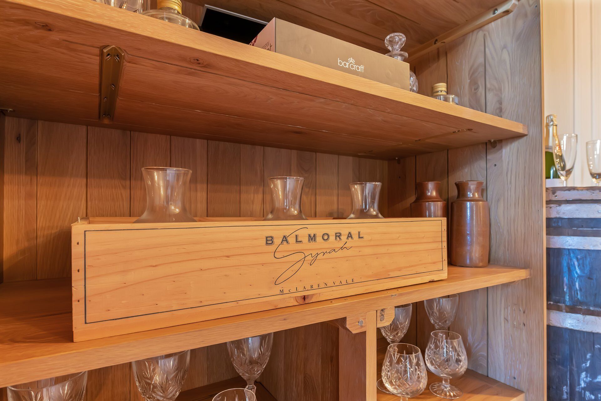 Ein Holzregal mit einer Barware-Box mit der Aufschrift 'BALMORAL' und 'McLaren Vale' an einer Holzwand.