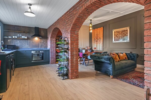 A modern kitchen with a built-in oven, a wine rack, and a dining area with a sofa and table.