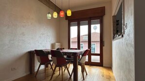 A dining area with a wooden table and chairs, a hanging light fixture, and a view of the outside through a window with a wooden frame. - [VE-Mestre Train Station] Relax&Zen Apartment (Venezia)