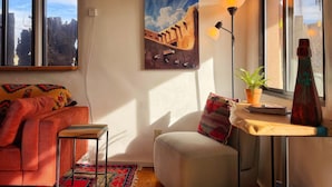A cozy living room with a sofa, a small table with a lamp, a painting, and a potted plant. - Historic Santa Fe Adobe - Walk to Plaza & Railyard District! (Santa Fe)