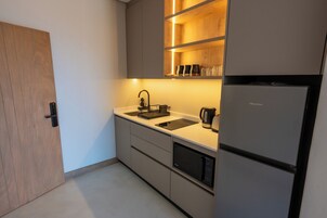 Una cocina moderna con un lavamanos integrado, una cafetera y un refrigerador.