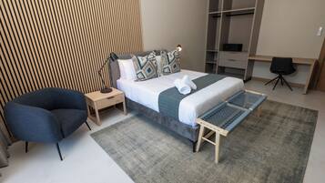 A modern bedroom with a bed, bedside tables, a chair, and a desk.