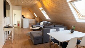 Een modern loft met een schuine kap, een eethoek, een zithoek en een keuken.