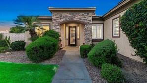 A residential house with a stone facade, a central entrance, and a well-maintained garden. - Terra Sol: Pool, Spa & Lakefront Serenity (Indio)