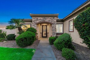 A residential house with a stone facade, a central entrance, and a well-maintained garden. - Terra Sol: Pool, Spa & Lakefront Serenity (Indio)