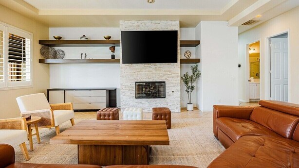 A living room with a fireplace, a flat-screen TV, and leather furniture. - Terra Sol: Pool, Spa & Lakefront Serenity (Indio)