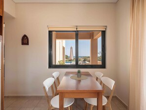 Ein Essbereich mit Tisch und Stühlen, ein Fenster mit Blick auf Pool und Landschaft sowie ein kleines dekoratives Element an der Wand.