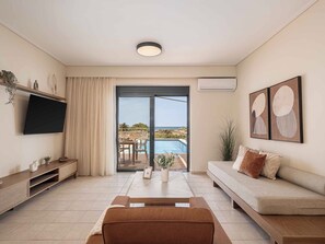 Ein Wohnzimmer mit Fernseher, Sofa und Blick auf Pool und Landschaft.