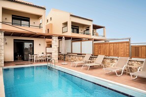 Un espace piscine avec des chaises longues, une table et un mur en pierre.