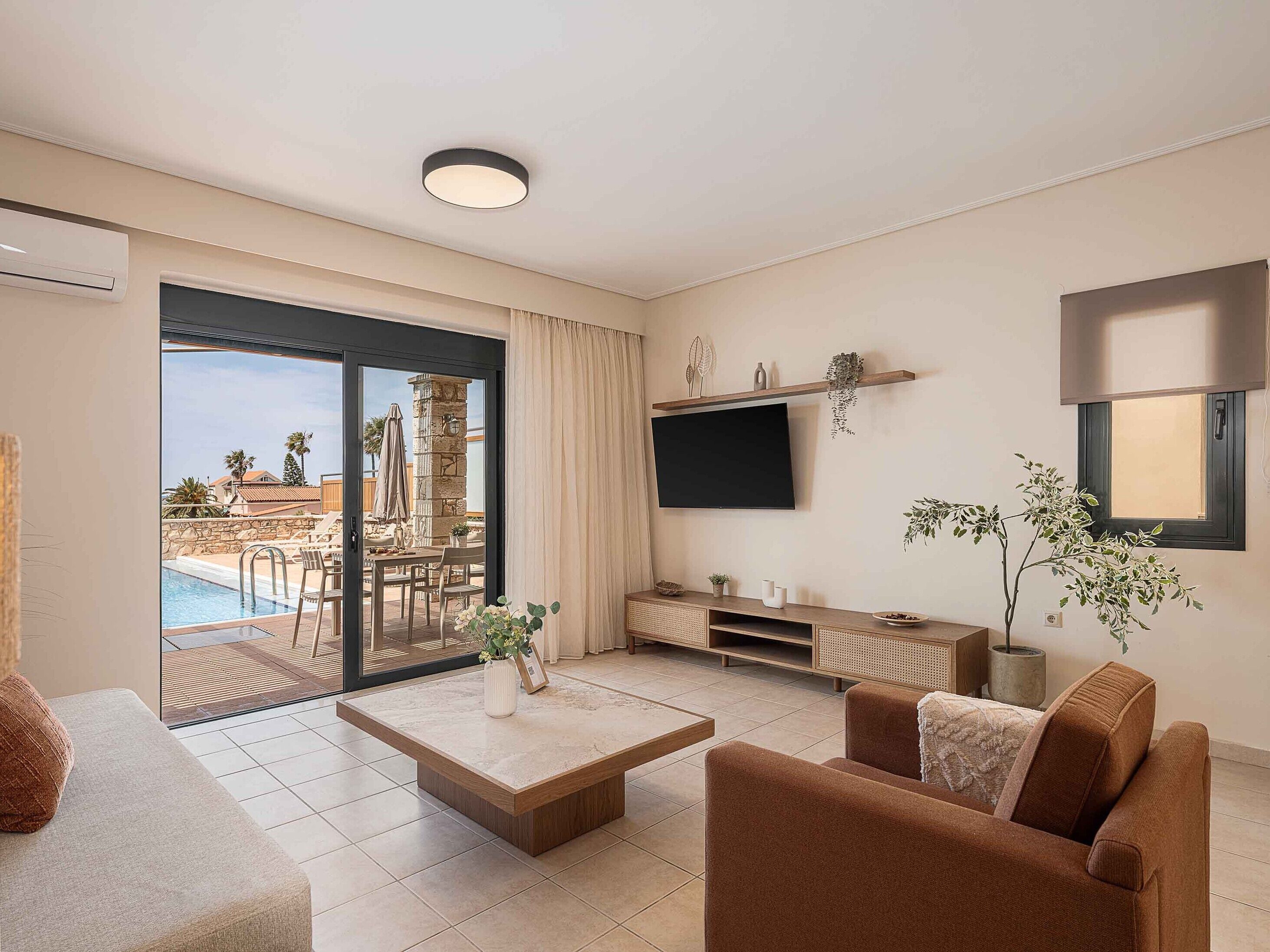 A modern living room with a pool view, a flat-screen TV, and a cozy seating area.