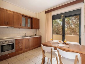 Eine moderne Küche mit Holzausstattung, einem Edelstahlbackofen und einem Essbereich mit Tisch für zwei Personen.