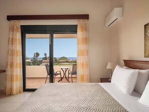 Ein Hotelzimmer mit Bett, Tisch, Stühlen und Meerblick, inklusive Klimaanlage.