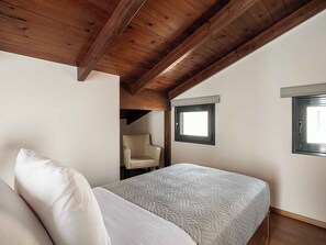 Ein Schlafzimmer mit einem Bett, einem Stuhl und einem Fenster.