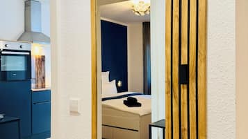 Ein Hotelzimmer mit einem großen Spiegel, einem Bett, einem Nachttisch und Blick auf den Küchenbereich.